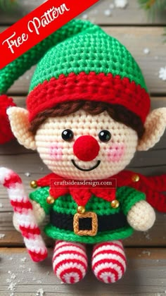 a crocheted christmas elf doll sitting on top of a wooden table next to candy cane