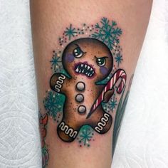 a gingerbread tattoo on the leg with candy canes and snowflakes around it