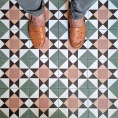 a person standing on top of a tiled floor with brown and green shoes in front of them