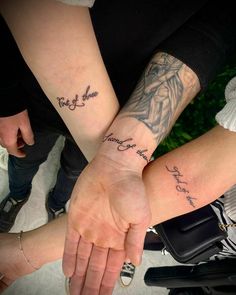 two people are holding hands with tattoos on their arms and one has the words together