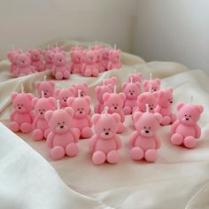 a bunch of pink teddy bears sitting on top of a white cloth covered tablecloth