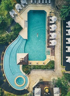 an aerial view of a swimming pool with lounge chairs and umbrellas