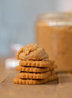 a stack of peanut butter cookies sitting on top of a wooden table next to a jar of peanut butter