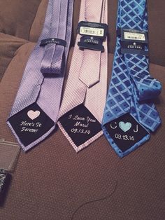 three different colored ties with tags on them sitting on a bed next to each other