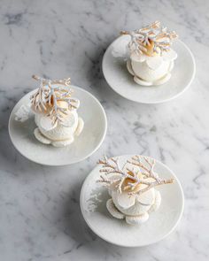 three white plates topped with desserts on top of a marble counter