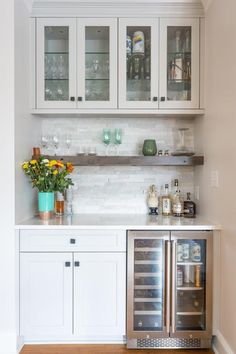 a kitchen with white cabinets and stainless steel refrigerator freezer combo in the center, filled with wine glasses