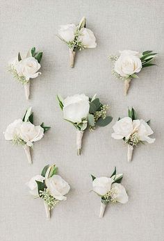 white flowers and greenery are arranged on a gray surface