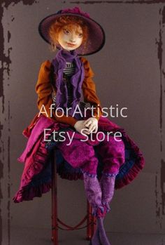 a doll sitting on top of a chair wearing a purple hat