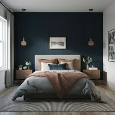 a bedroom with dark blue walls and white bedding, wooden flooring, two framed pictures on the wall