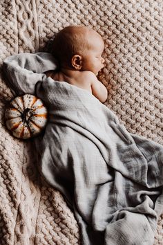 a baby wrapped in a blanket sleeping on top of a bed