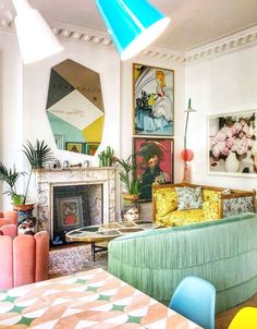 a living room filled with lots of furniture and paintings on the wall next to a fire place