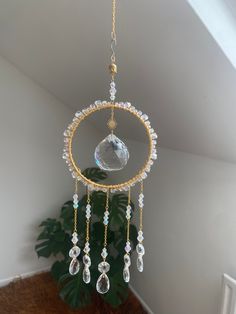 a gold and crystal wind chime hanging from a ceiling in a room next to a potted plant