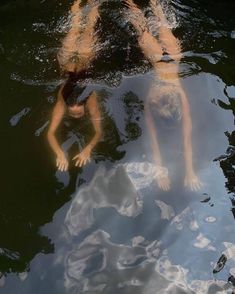 two people floating in the water with their hands on each other's back legs