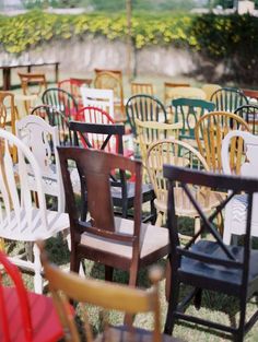 a bunch of chairs that are sitting in the grass with one chair up against it's back