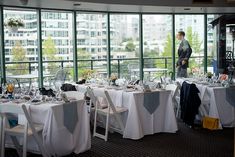 a room filled with lots of tables covered in white table cloths and place settings