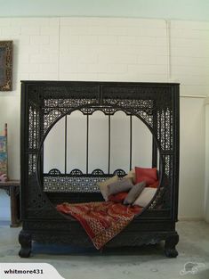 an iron bed with pillows on it in a room