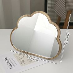 a mirror that is shaped like a cloud on top of a table with measurements for it