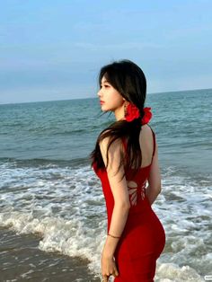 a woman in a red dress standing on the beach