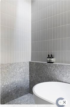 a white bath tub sitting next to a tiled wall