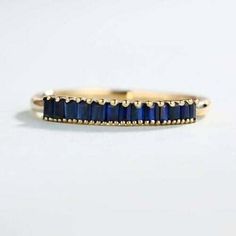 a yellow gold band with blue sapphire stones on the inside and outside, set against a white background