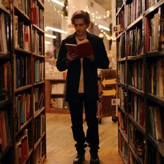 a young man is reading a book in the middle of a library filled with books