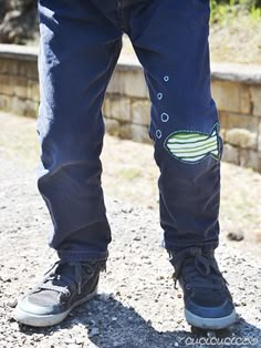 a person wearing blue jeans and black shoes standing on the ground with their hands in his pockets