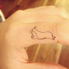 a hand with a small dog tattoo on it's left thumb and the outline of a dog