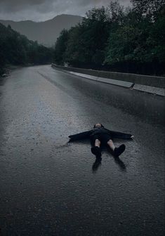 a person laying on the side of a wet road