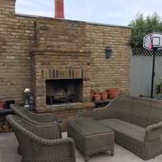 an outdoor living area with wicker furniture and a brick fire place in the background