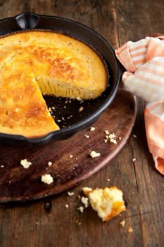 a skillet filled with bread on top of a wooden cutting board