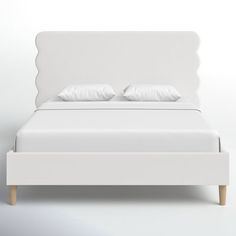 a white bed with two pillows on top of it