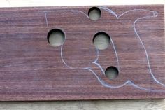 a wooden sign with two holes in the shape of a cat's head on it