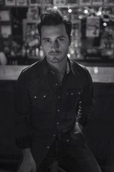 a man sitting in front of a bar with his hands on his hips and looking at the camera