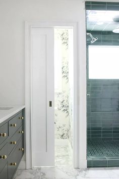 a bathroom with marble counter tops and green tile on the shower wall, along with an open door