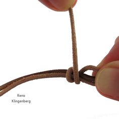 a person is tying a knot on a string with one hand and another hand holding the rope