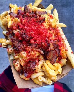 a hot dog covered in ketchup and macaroni on top of a paper bag