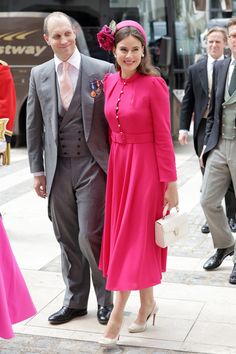 a woman in a pink dress standing next to a man in a suit