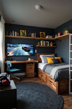 a bedroom with a bed, desk and television on the wall next to a window