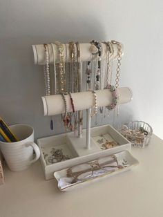 a white tray holding jewelry and glasses on top of a table next to a cup