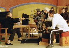 a group of people sitting around a table in front of a camera set up for filming