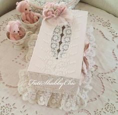 two teddy bears are sitting next to a book on a doily covered tablecloth