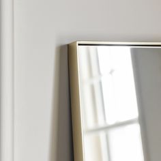 a mirror hanging on the side of a wall next to a white door and window