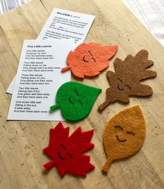 four felt leaf shapes sitting on top of a wooden table next to a piece of paper