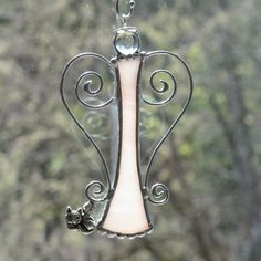 an angel shaped glass piece hanging from a window sill with trees in the background