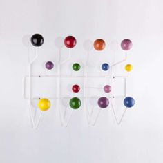 a group of colorful balls hanging on a white wall next to a rack with hooks