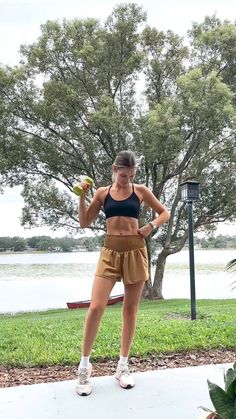 a woman is standing on the sidewalk with her hands on her hips and holding two bananas