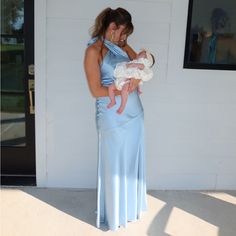 a woman in a blue dress holding a baby