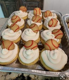 cupcakes with white frosting and red ribbon on top in a tin pan