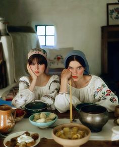 two women sitting at a table with bowls of food and chopsticks in front of them