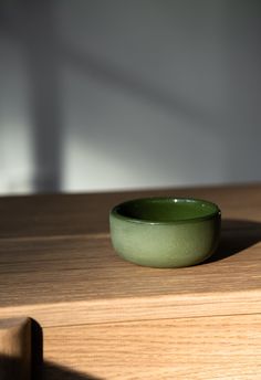 a green bowl sitting on top of a wooden table